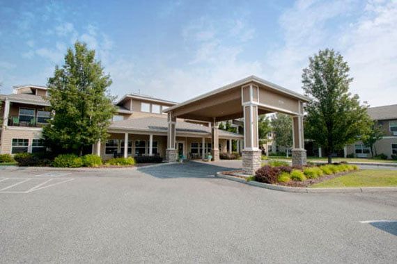 A spacious building entrance with a covered driveway and surrounding greenery.