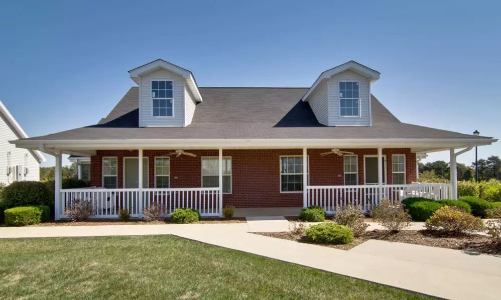 A charming brick house with a front porch and dormer windows.