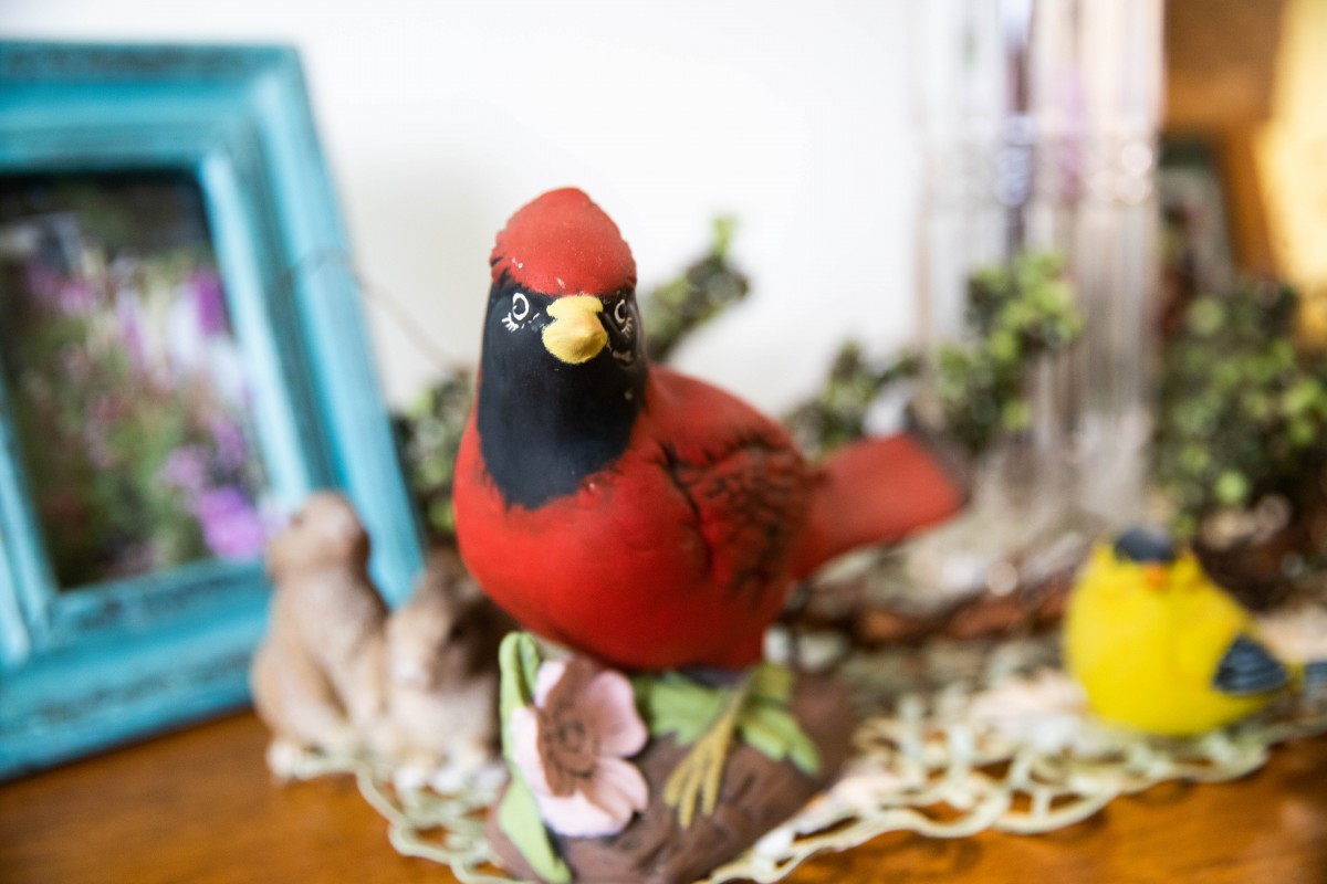 A decorative cardinal figurine displayed on a table with floral accents.