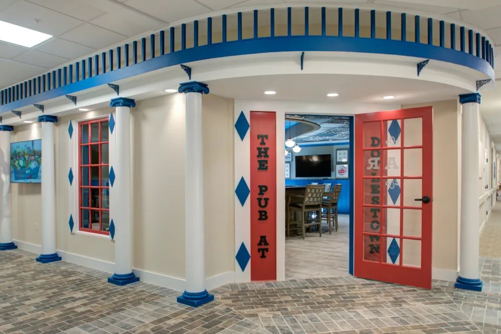 A creatively designed interior space featuring decorative columns and a vibrant color scheme, leading into a gaming area.