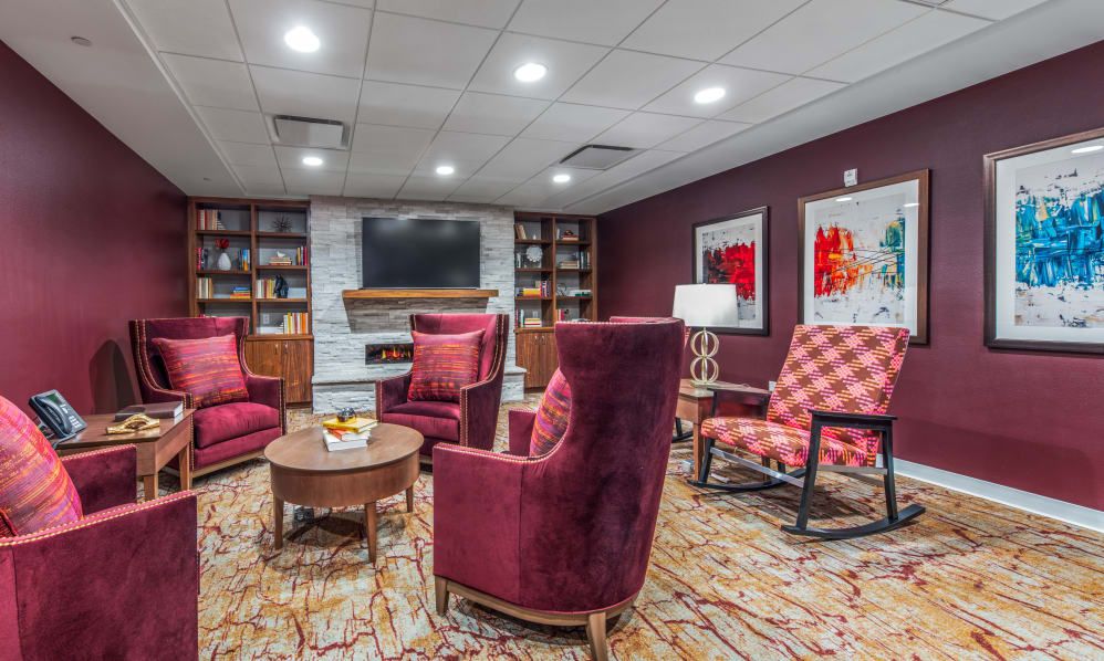 A cozy living room with plush armchairs, a fireplace, and a well-stocked bookshelf.