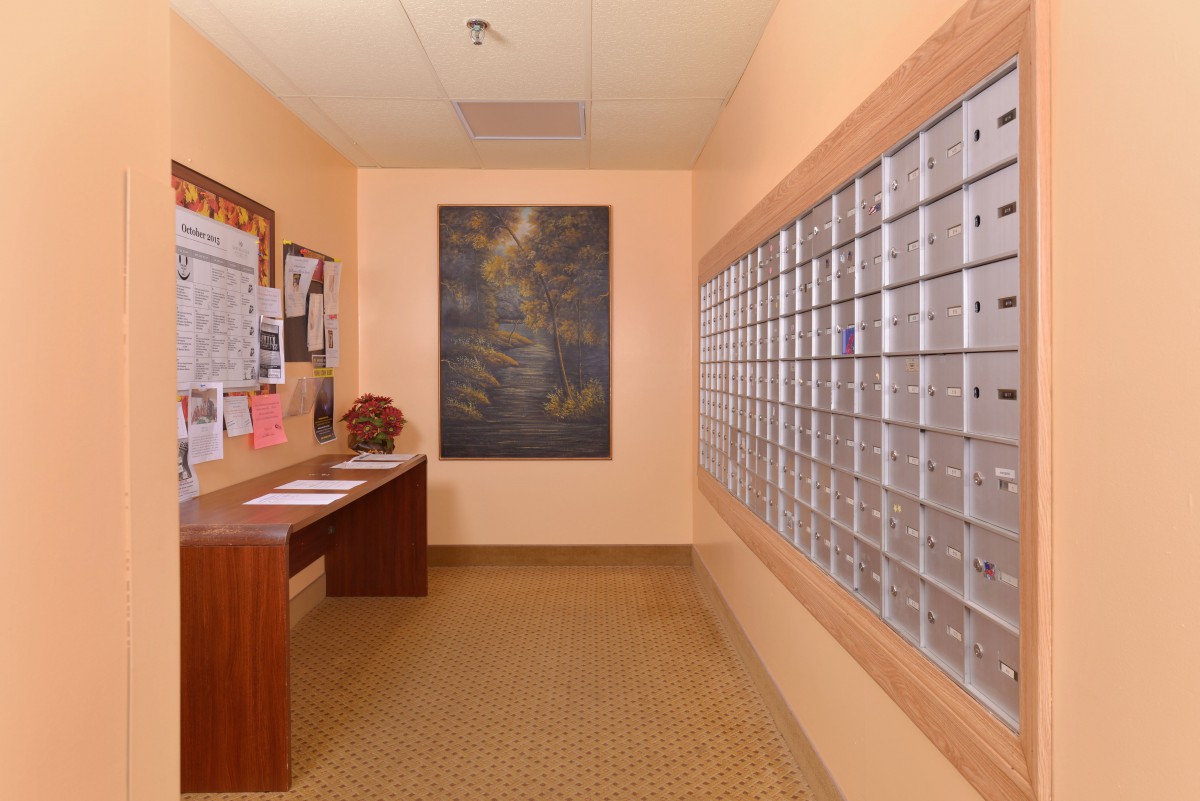 A mailroom with a row of mailboxes and a bulletin board on the wall.