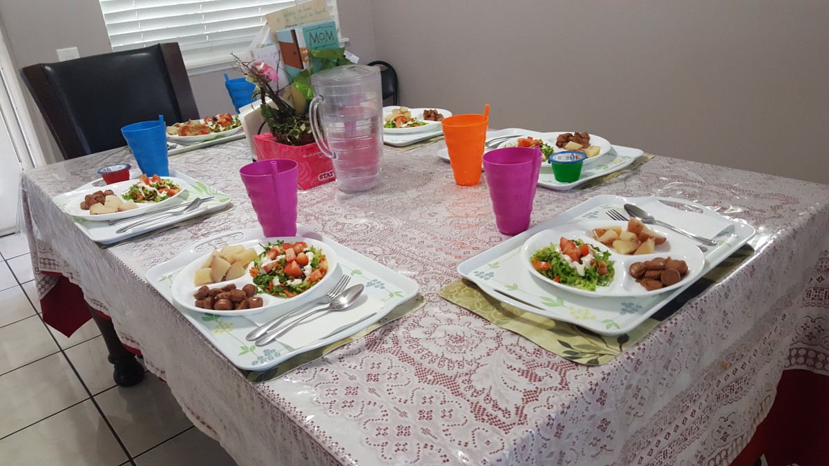 A dining table set with plates of food, including salad and colorful cups.