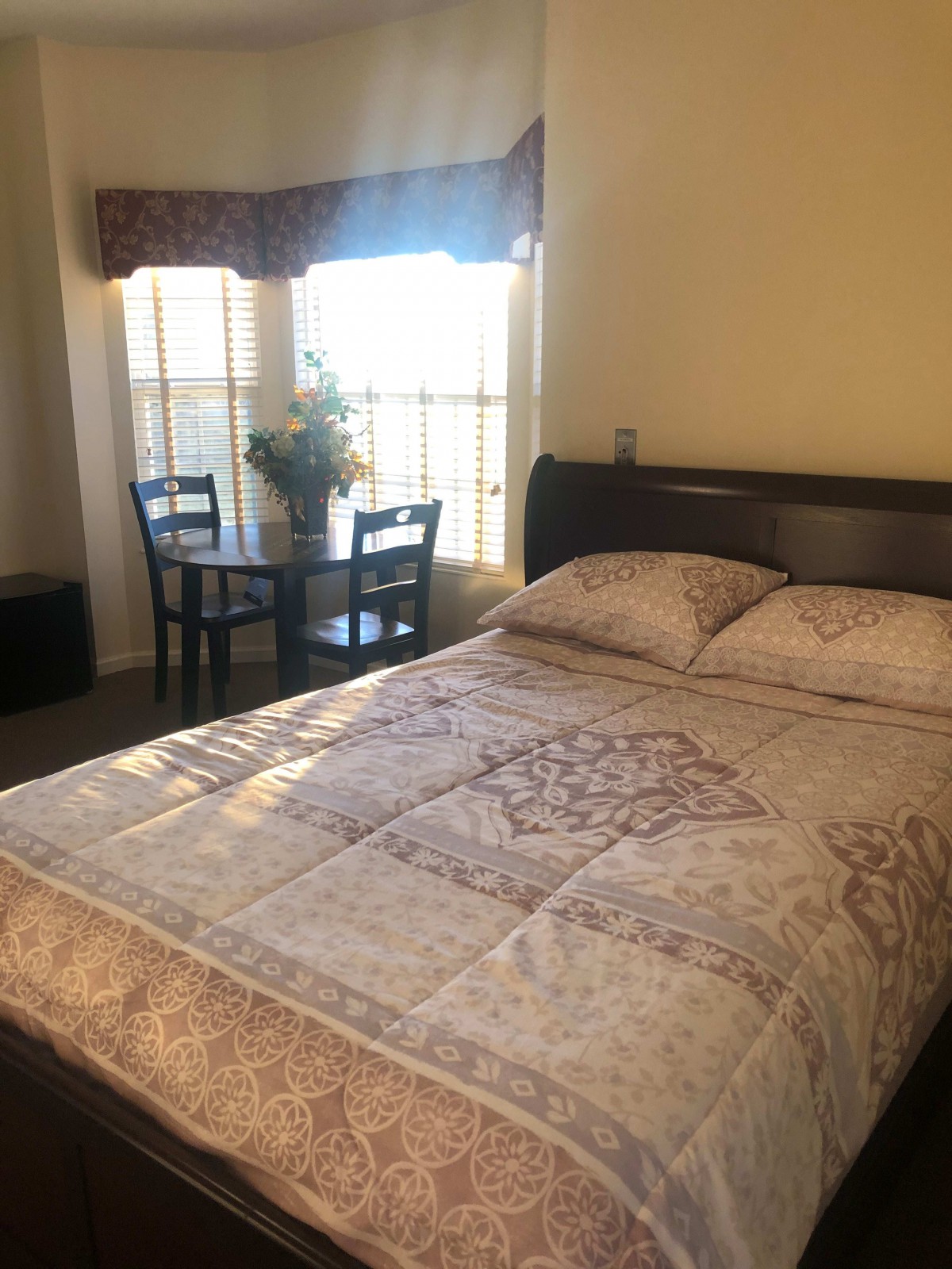 A cozy bedroom with a large bed and a small dining table by the window.