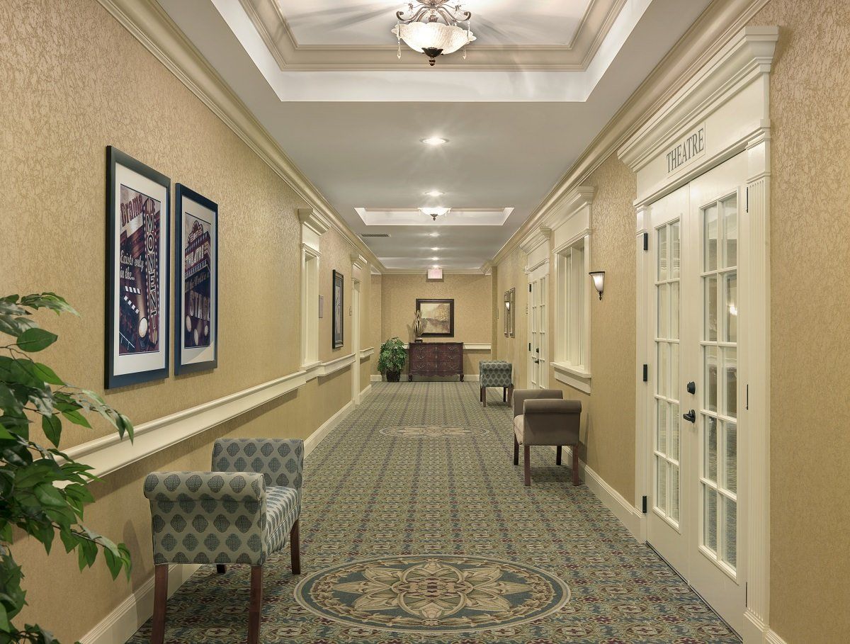 A well-lit hotel hallway with elegant decor and seating areas along the sides.