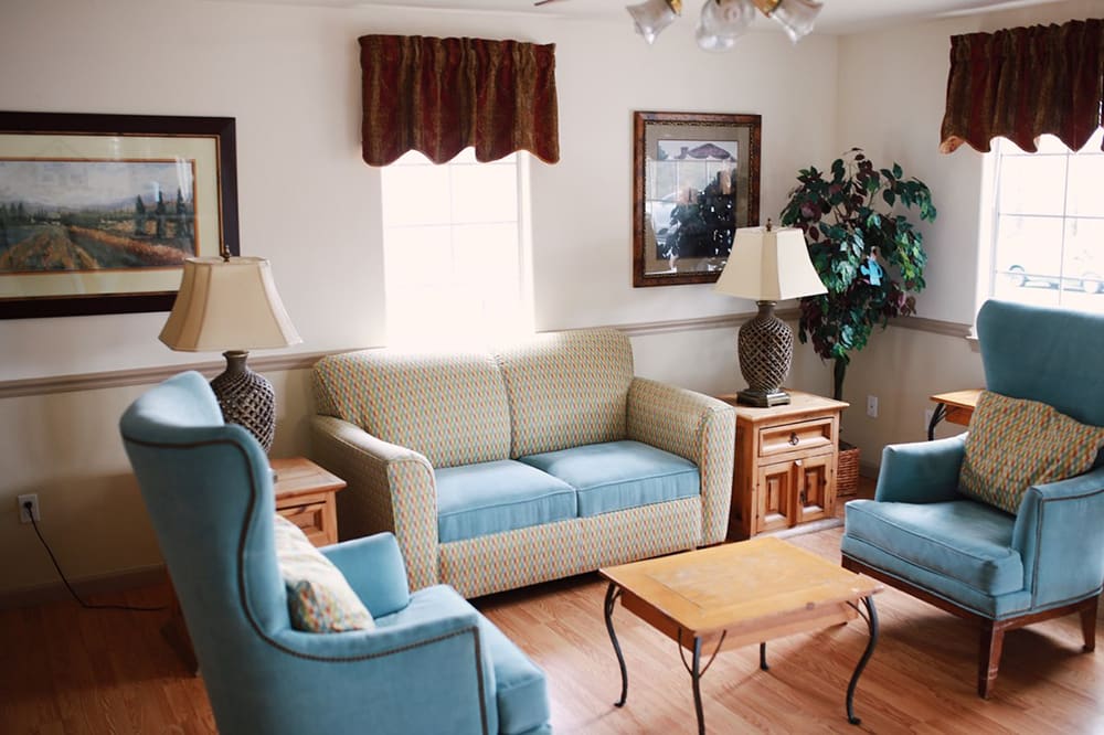A cozy living room with a beige and blue sofa set, wooden coffee table, and decorative lamps.