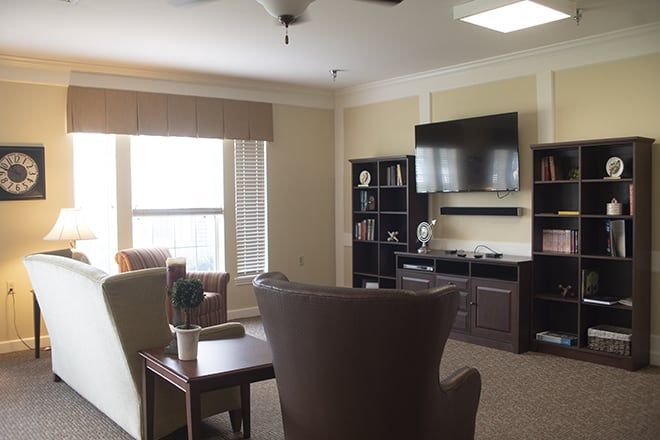 A cozy and modern living room with a television, bookshelf, and comfortable seating.