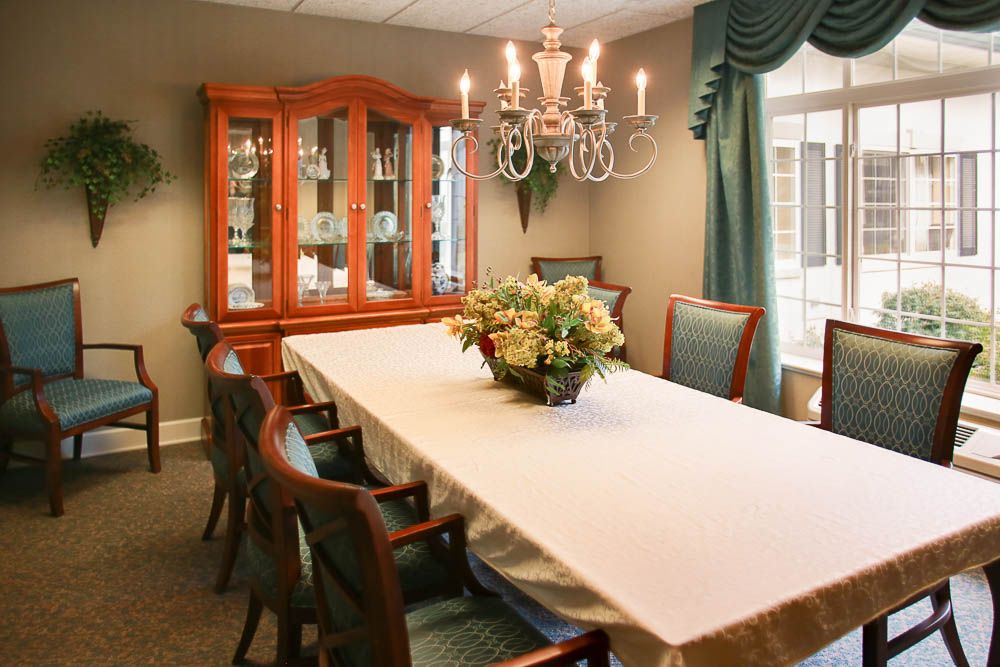 A well-decorated dining room featuring a long table with chairs, a chandelier, and a china cabinet.