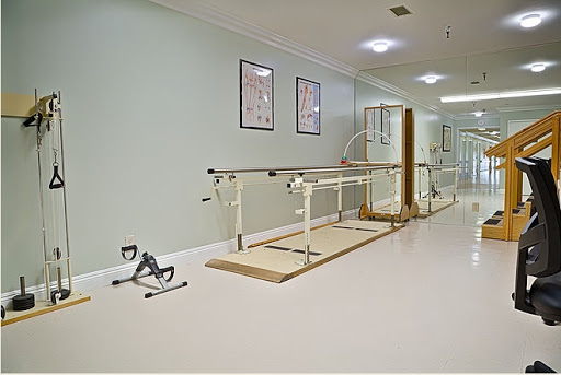 A rehabilitation therapy room featuring parallel bars and exercise equipment for patient recovery.