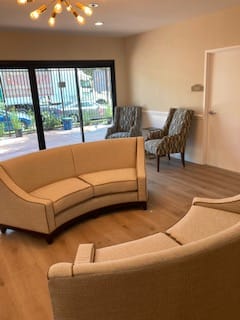 A cozy living room setting with curved sofas and large windows.