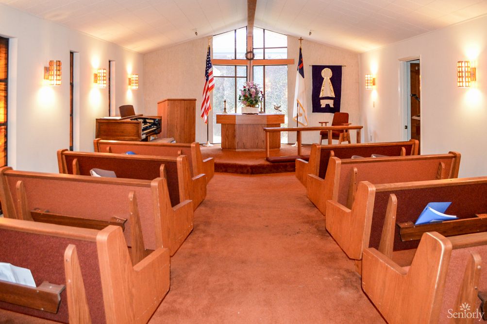 Interior view of a church with wooden pews and an altar at the front.