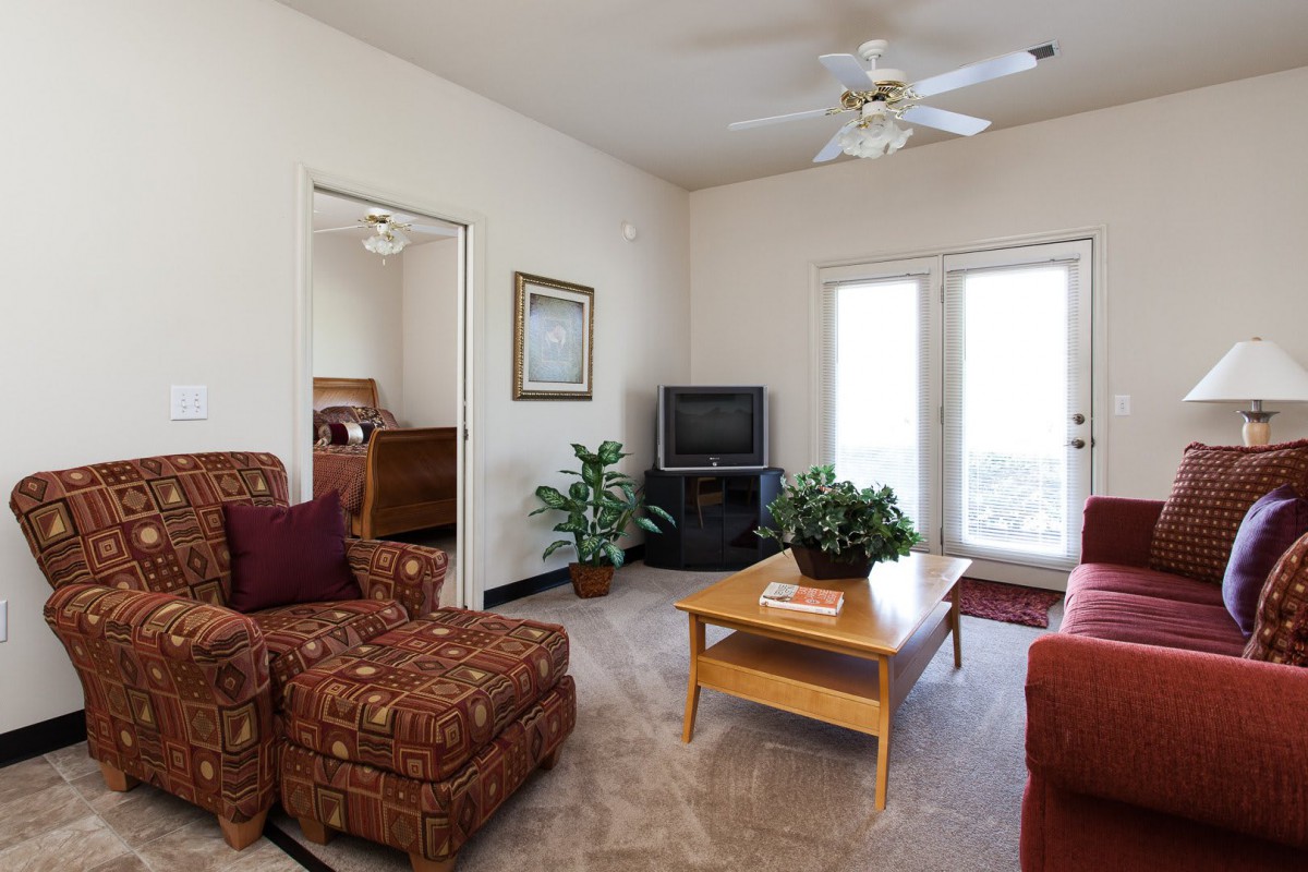 A cozy living room with a patterned armchair, coffee table, and TV.