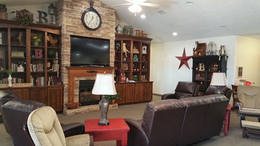A cozy living room featuring a stone fireplace, built-in bookshelf, and comfortable seating arrangements.