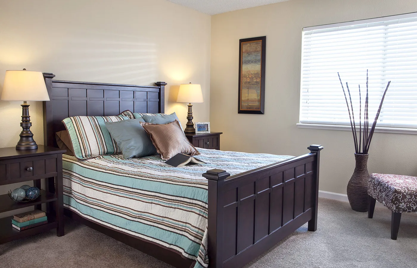 A cozy bedroom with a striped bedspread and wooden furniture.