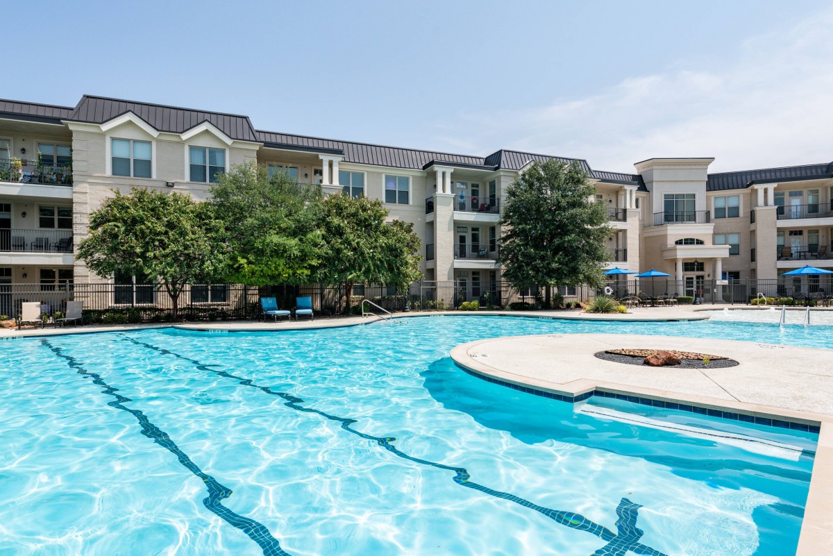 A sunny day at a modern apartment complex with a large outdoor swimming pool.