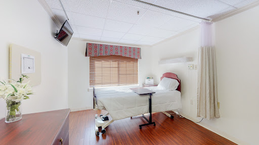 A well-lit and clean hospital patient room with a bed, television, and window.