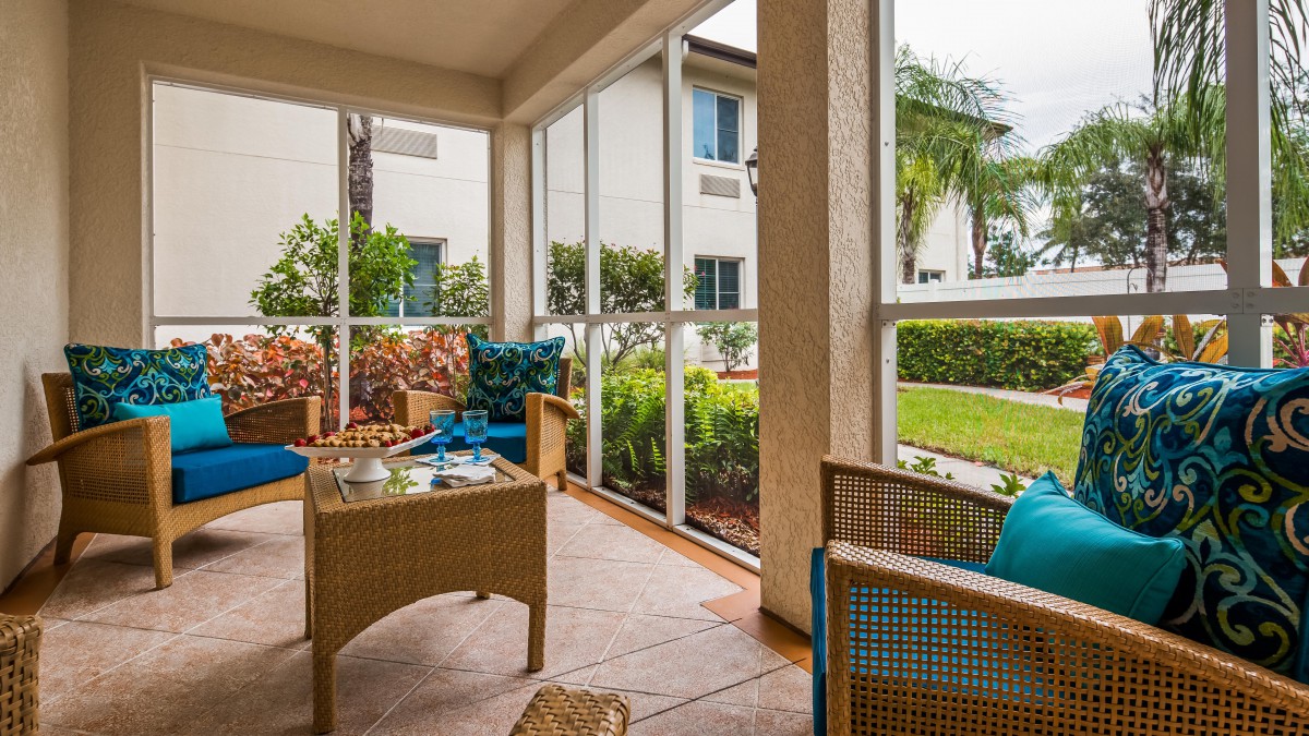 A cozy screened patio with comfortable seating and lush greenery.