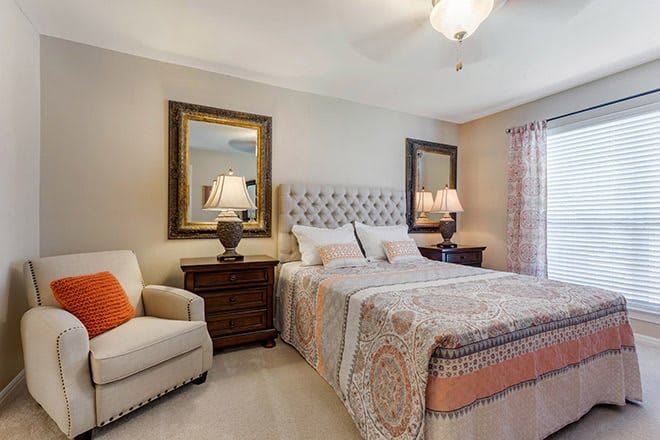 A cozy bedroom with elegant decor, featuring a plush bed, stylish armchair, and warm lighting.