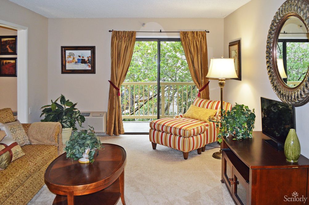 A cozy living room with a striped chair, warm lighting, and greenery.