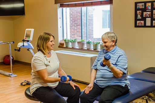 A healthcare professional guides an elderly individual in a weightlifting exercise, promoting strength and wellness.