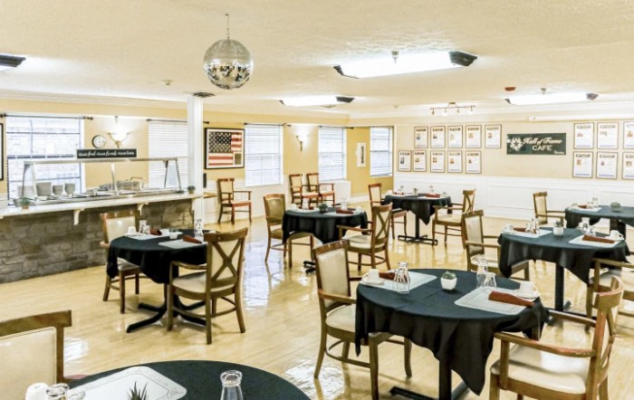 A well-lit dining area with neatly arranged tables and chairs, featuring simple decor.