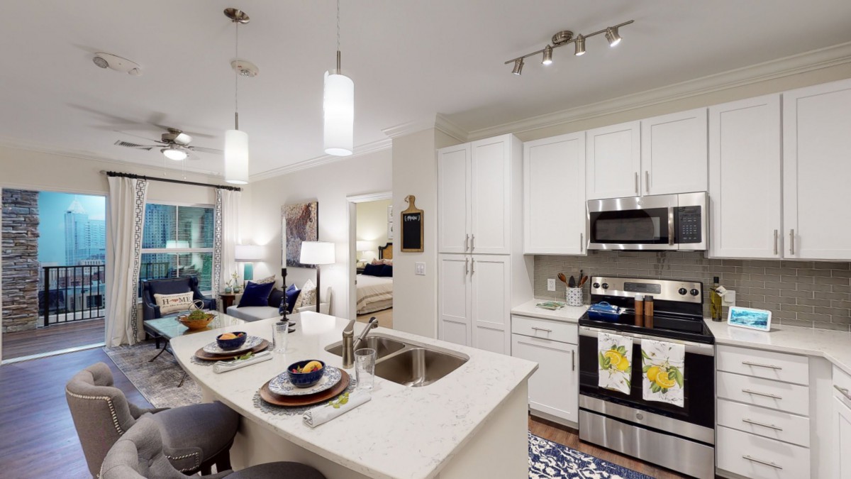 A modern kitchen with white cabinets and an island counter, featuring integrated appliances in an open layout.