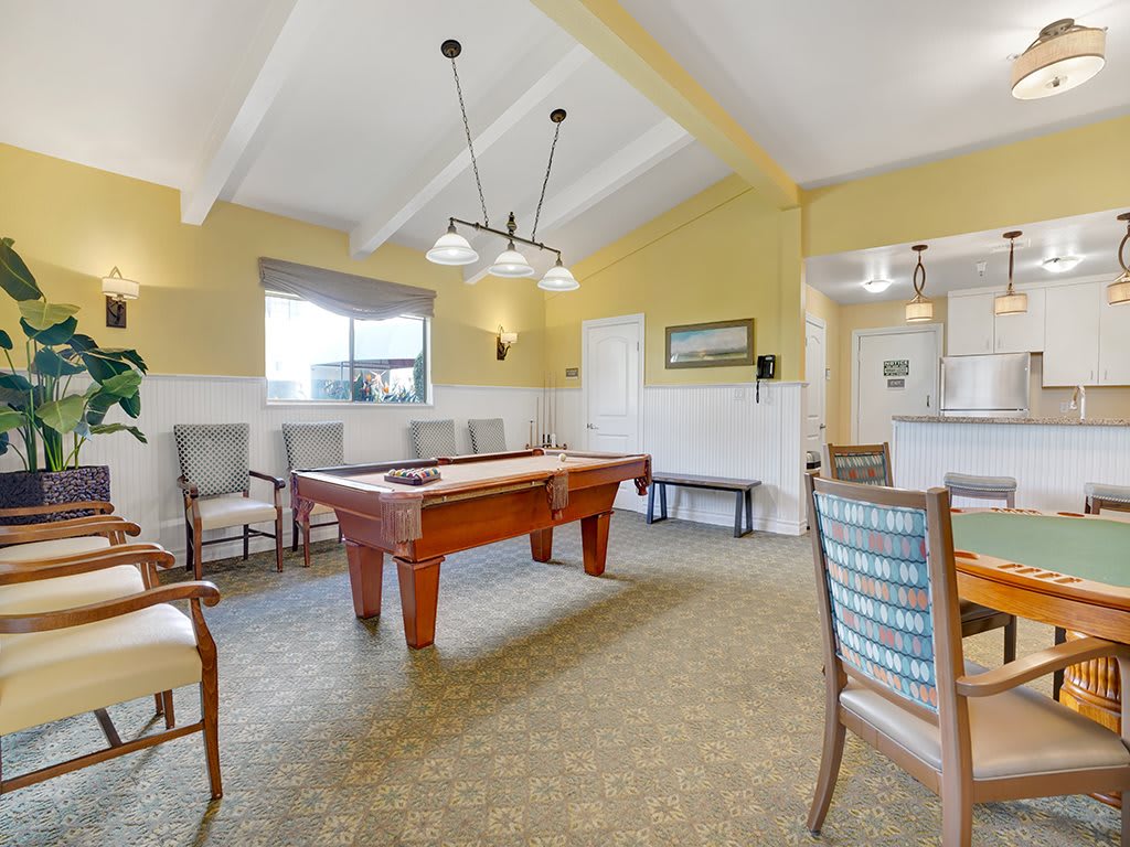 A well-lit game room featuring a pool table and various seating options.