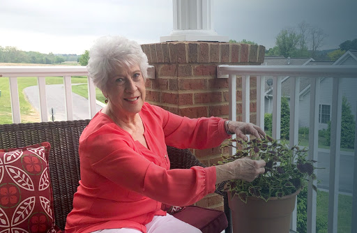 An elderly woman enjoying her time gardening on the porch.