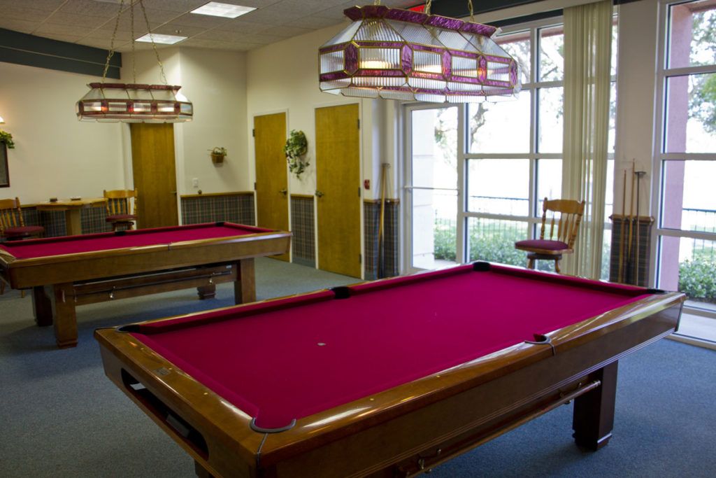 A recreational game room featuring two billiard tables with red felt.