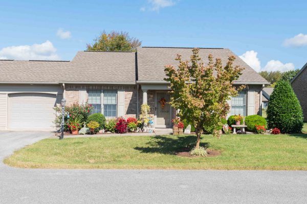A suburban house with a well-maintained front yard and landscaping under a clear blue sky.