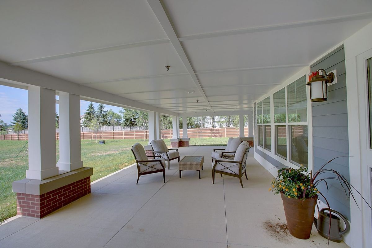 A spacious covered patio with comfortable seating and a garden view.