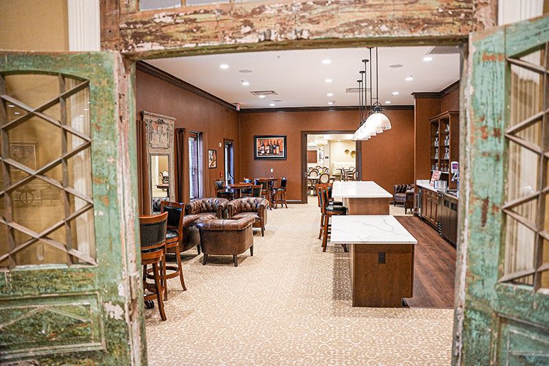 A cozy lounge with comfortable seating and a bar counter, featuring warm wooden accents and pendant lighting.