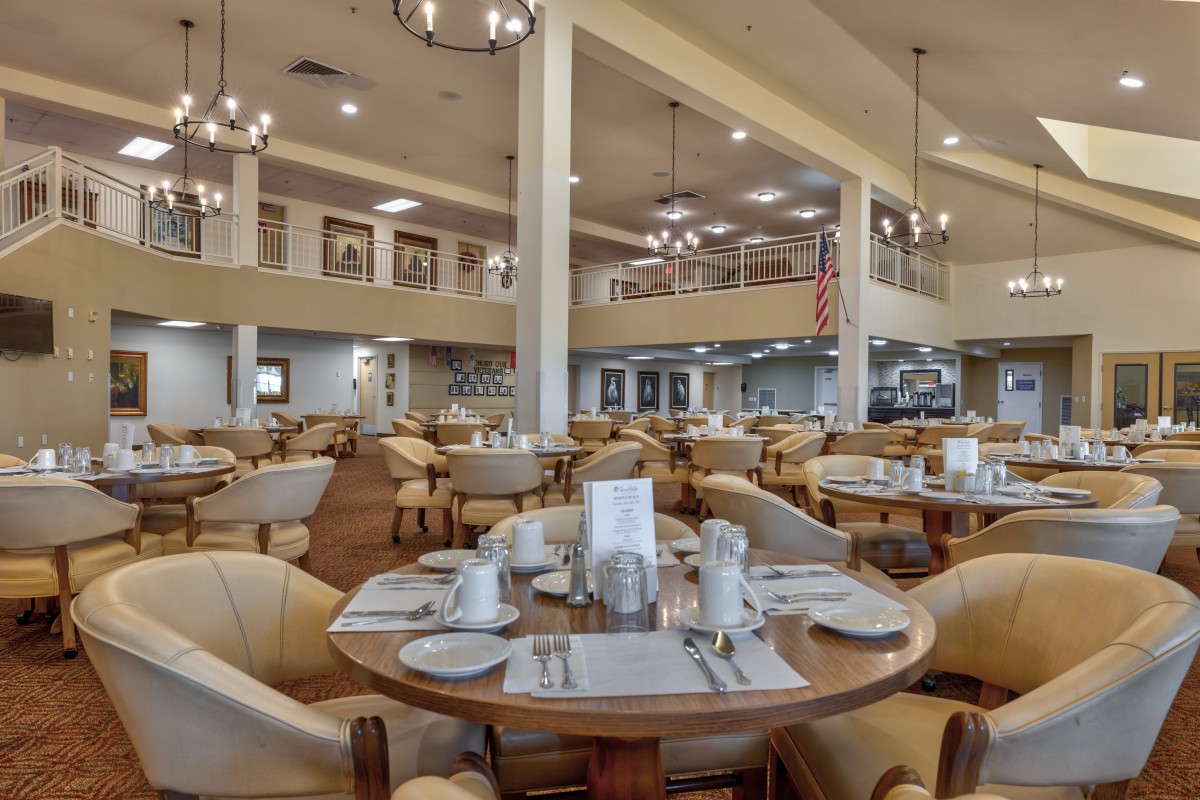 A spacious and elegantly furnished restaurant dining area with neatly arranged tables and comfortable seating.
