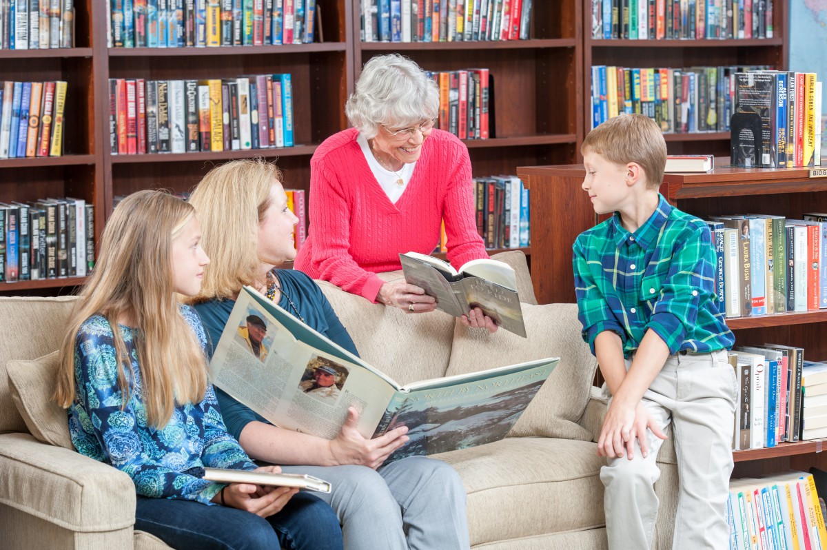 A multigenerational family enjoying reading together in a library setting.