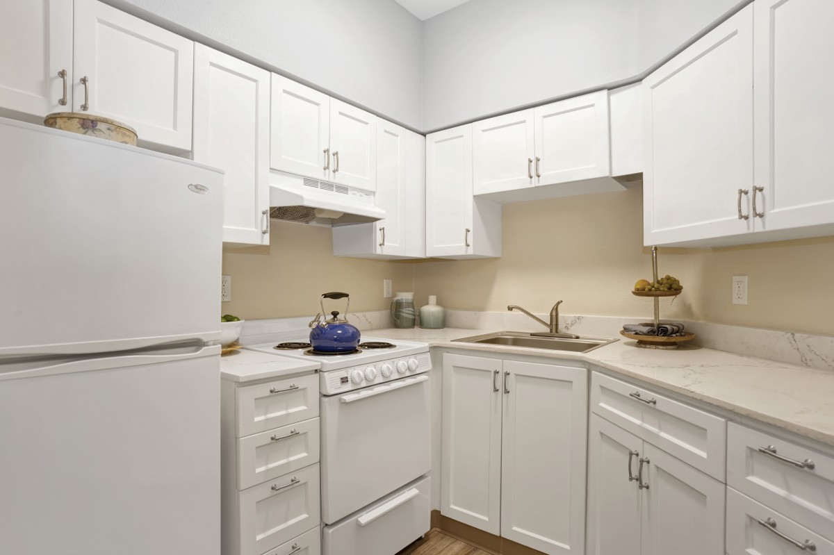 A modern kitchen with white cabinets and standard appliances.