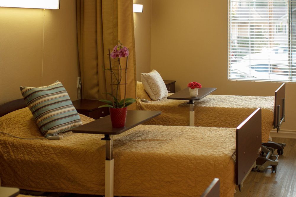 A hospital room with two neatly arranged beds and bedside tables.