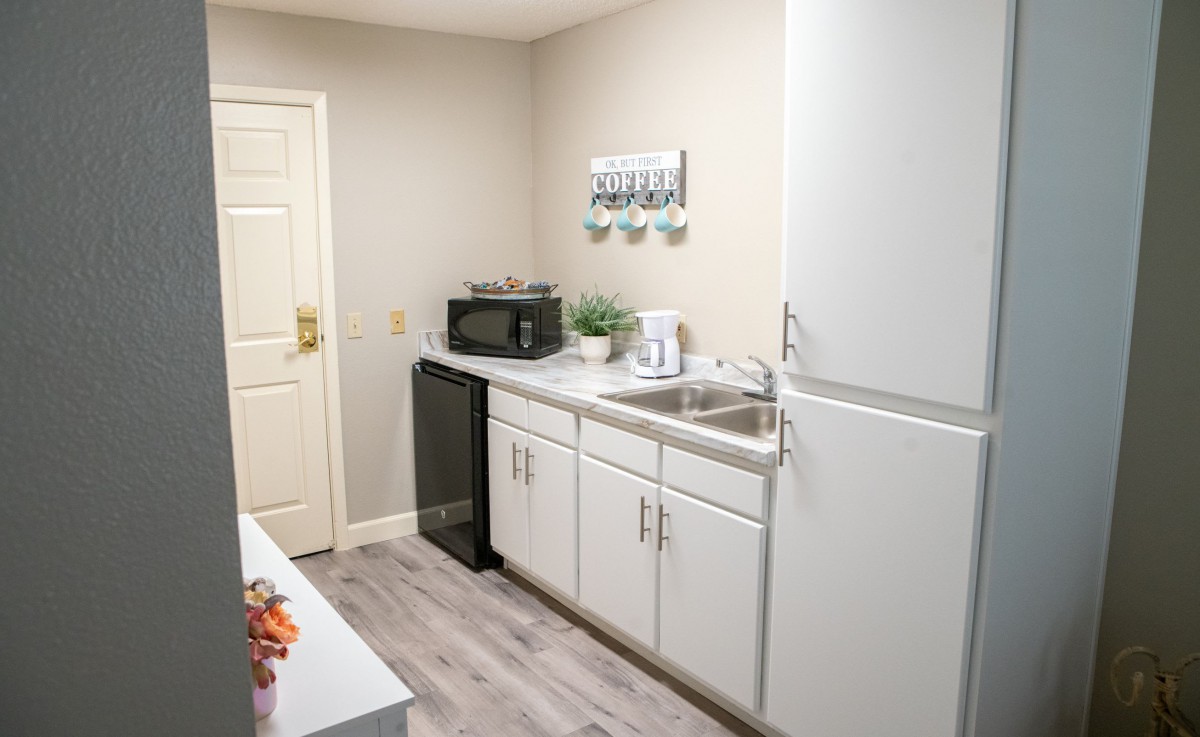 A minimalist kitchen with white cabinets, a microwave, fridge, and decorative elements.