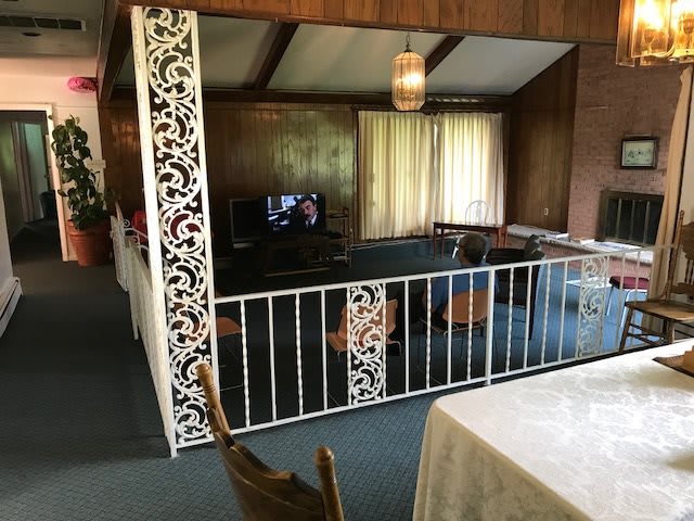 A retro-styled living room with wood paneling and decorative railing.