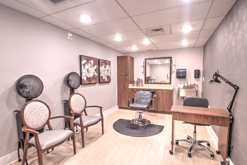 A well-lit and neatly arranged salon interior with chairs, a mirror, and styling equipment.