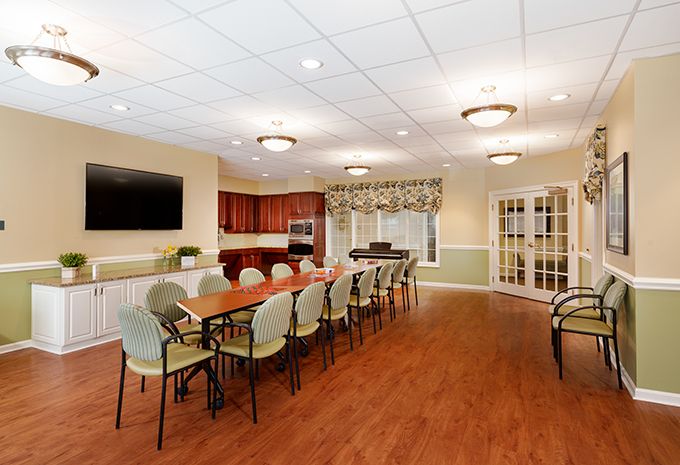 A modern conference room with a large table, seating, and a television.