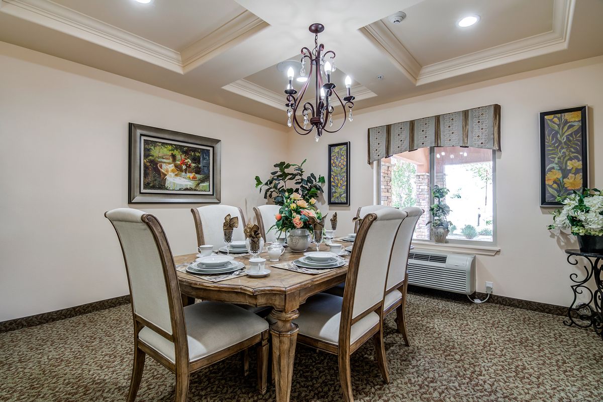 A beautifully decorated dining room with a wooden table set for a meal, surrounded by elegant chairs and illuminated by a chandelier.