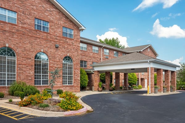 A brick exterior building with a landscaped entrance and covered driveway, possibly a hotel.