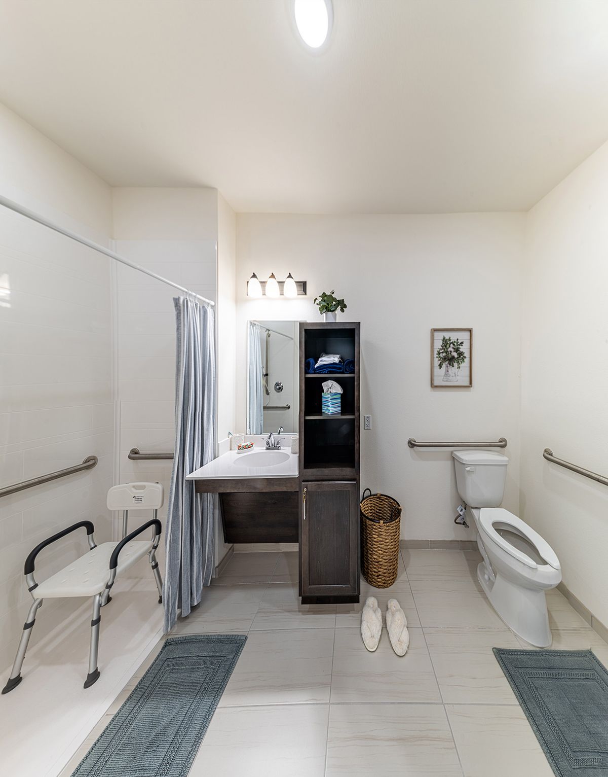 A clean and organized bathroom with a shower, toilet, sink, and various bathroom accessories.