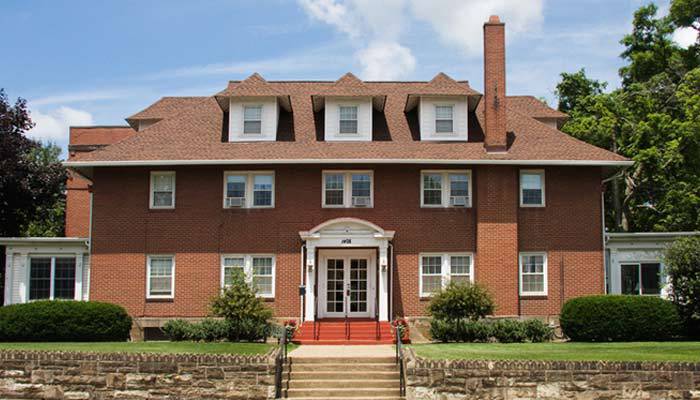 A large brick house with multiple dormer windows and a chimney.