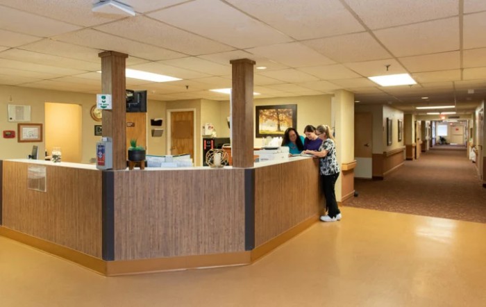 A hospital reception area with staff attending to work at the desk.
