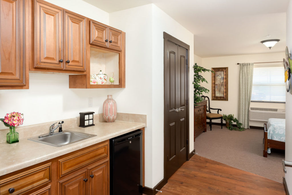 A cozy interior view featuring wooden kitchen cabinets, a small sink, and a countertop leading into a living space.