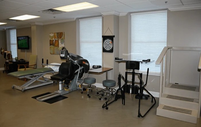 A rehabilitation room equipped with various therapy devices and a dartboard for therapeutic exercises.
