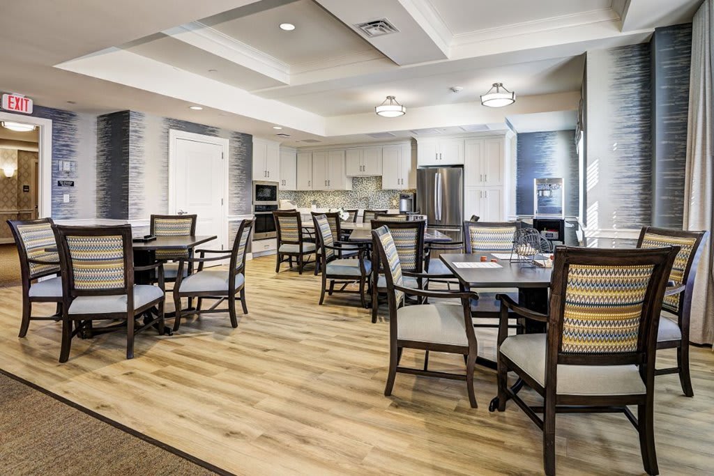 A modern dining area with neatly arranged tables and chairs, adjacent to a kitchen.