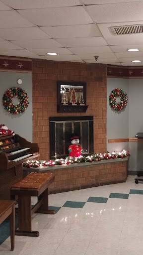 A cozy holiday-themed interior featuring a decorated fireplace, wreaths, and a cheerful snowman.
