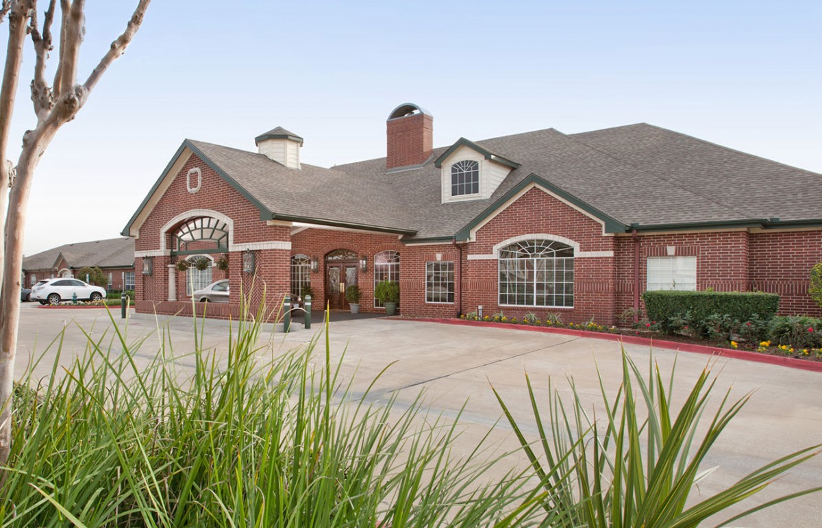 A charming red brick building with a landscaped driveway and traditional architectural features.